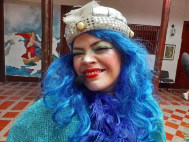 Mujer disfrazada con cabello azul, gorro blanco con brillos